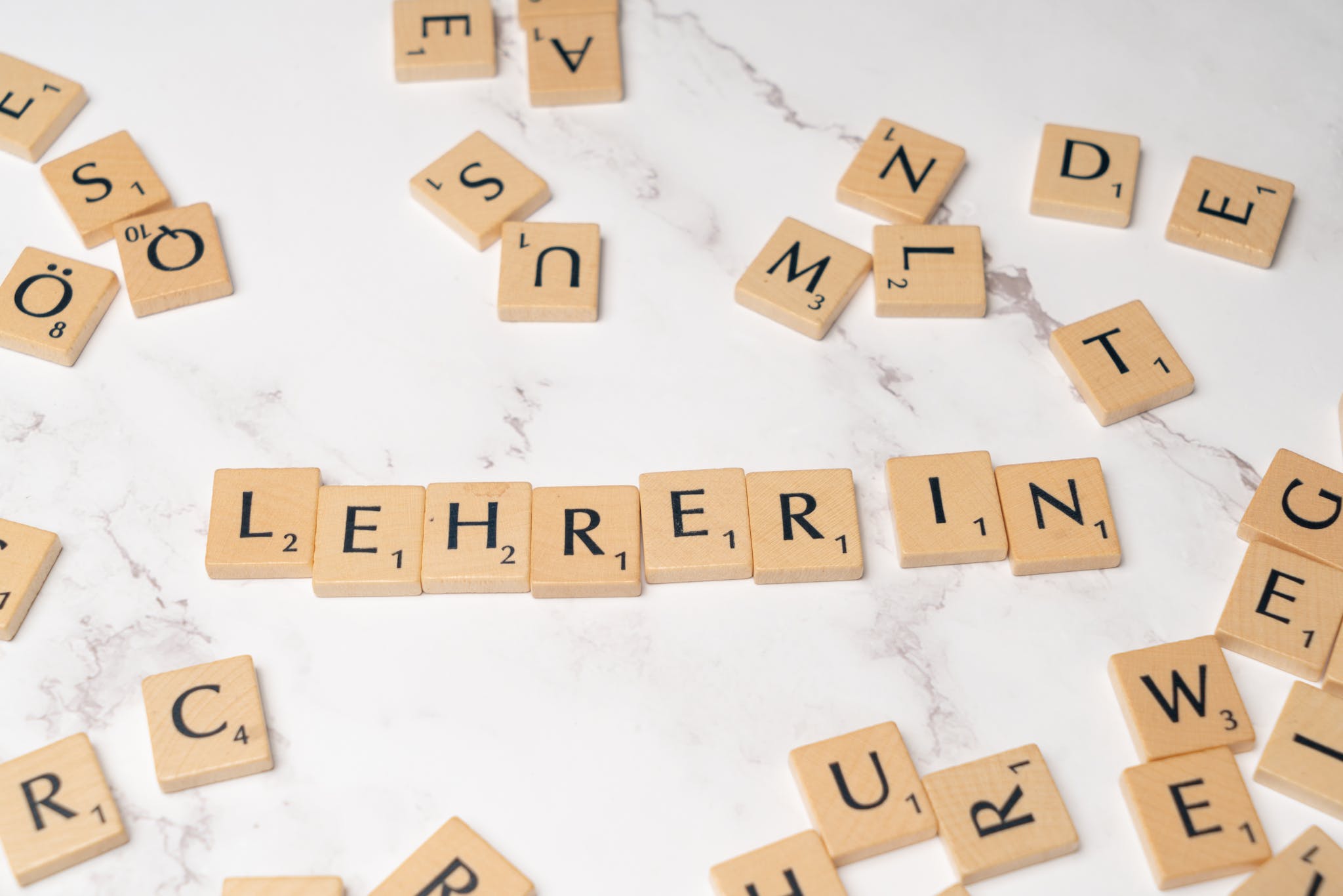 Scrabble tiles spelling lehrerin on a white marble surface